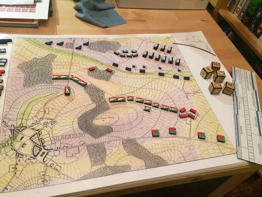 Kriegsspiel Mesa con un mapa topográfico antiguo, reglas de medición metálicas y pequeños bloques rectangulares de colores que representan unidades militares