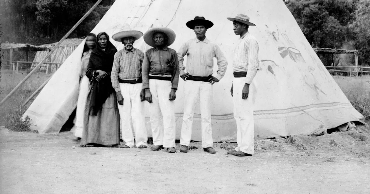 Personas yaquis frente a una vivienda tradicional en una fotografía histórica
