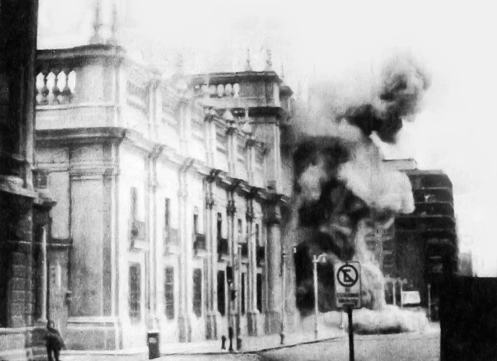 Fachada del Palacio de La Moneda envuelta en humo durante el bombardeo, en blanco y negro